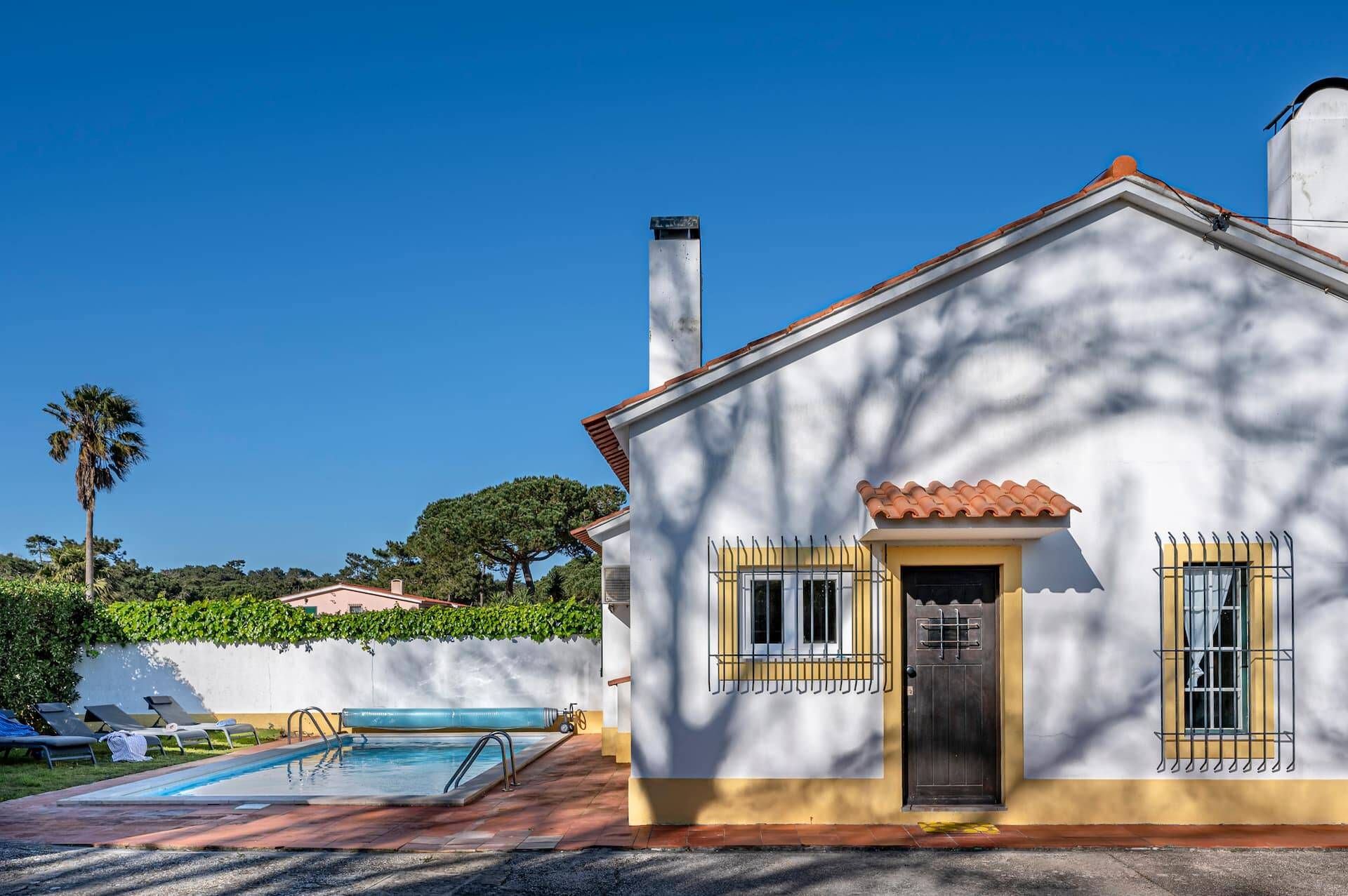 Una casa con piscina, una puerta y ventanas.