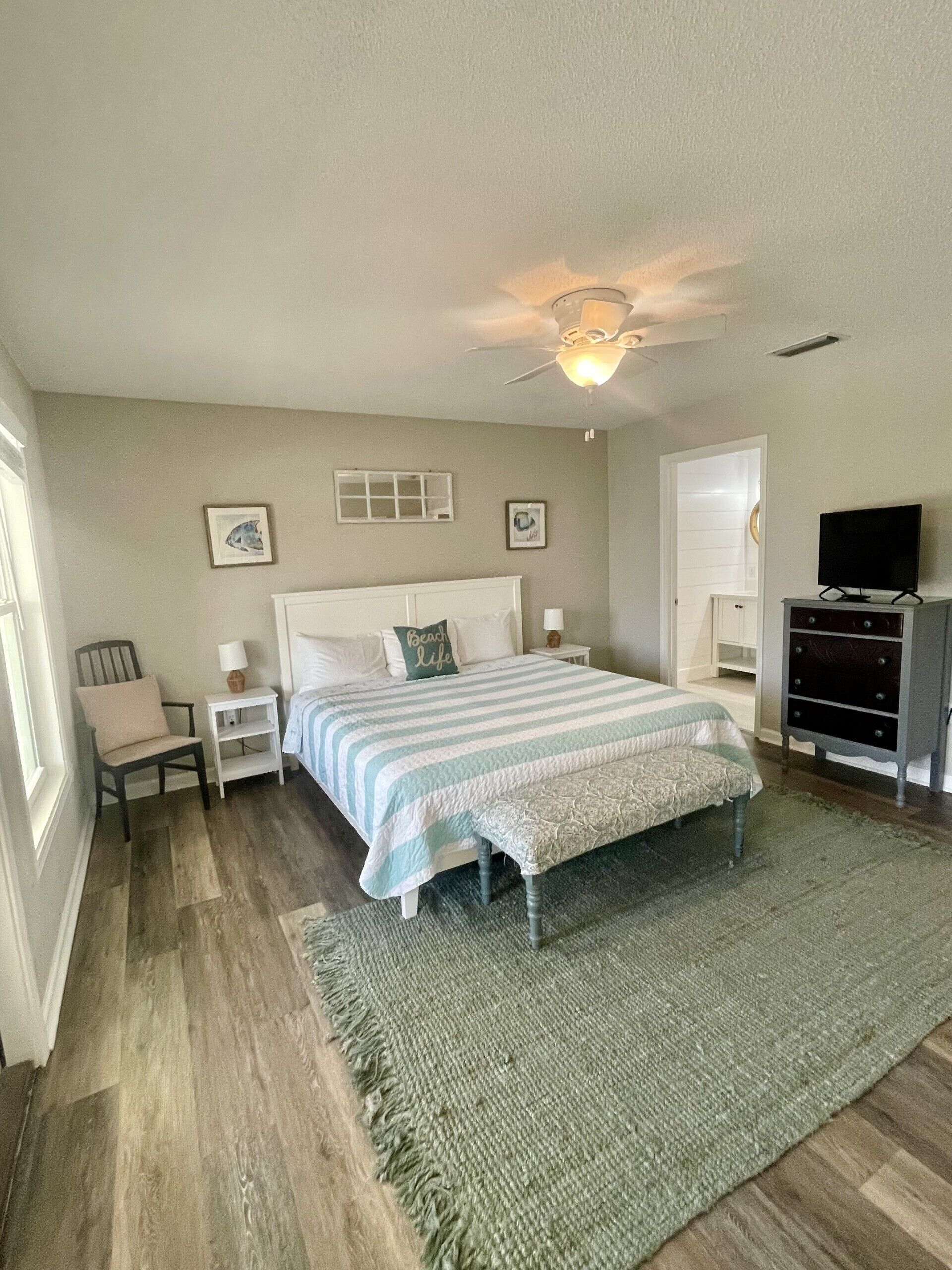 A bedroom with a bed, nightstands, a dresser, a ceiling fan, and a television.