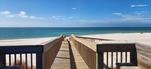 A wooden boardwalk leading to a beach with clear skies.