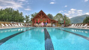 A swimming pool with lounge chairs and a wooden pavilion in the background. - Cabin w/Breathtaking Views, Hot Tub & Game Room (Sevierville)