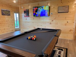 A pool table with balls, a television mounted on the wall, and a framed poster. - Cabin w/Breathtaking Views, Hot Tub & Game Room (Sevierville)