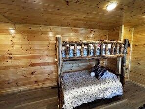 A bunk bed with a wooden frame and a patterned bedspread.