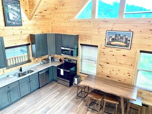 A compact kitchen with wooden walls, a built-in oven, a microwave, and a sink.