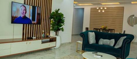 A modern living room with a TV, sofa, coffee table, and decorative plants.