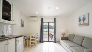 A modern kitchen with white cabinets, a dining table with chairs, and a grey sofa. - Apartamentos Vale de Carros by Umbral (Albufeira)