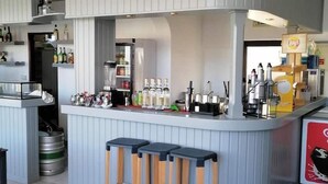 A bar area with stools, a refrigerator, and shelves with bottles. - Apartamentos Vale de Carros by Umbral (Albufeira)