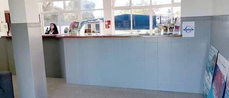 A reception area with a counter, a chair, and a window with a view of the outside.