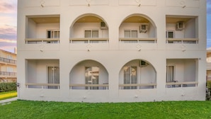 A multi-story building with balconies and arched windows, surrounded by green grass. - Lefteris Insta-worthy Studio With Balcony (Rhodes)