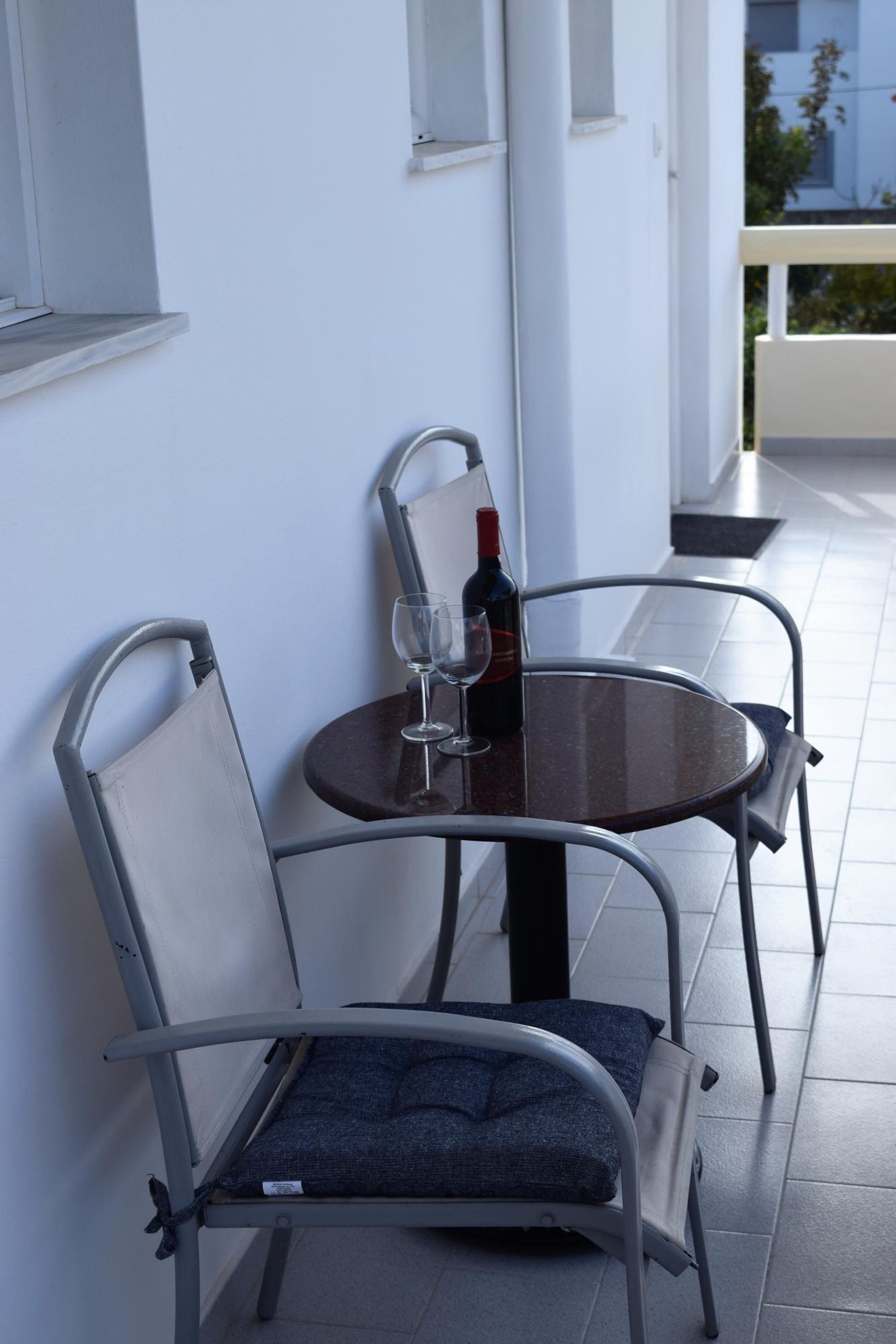 A table with two chairs, a wine bottle, and a glass on a balcony.
