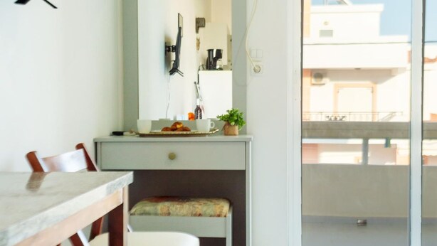 A room with a dining table, a bench, a mirror, and a sliding glass door leading to a balcony. - Lefteris Insta-worthy Studio With Balcony (Rhodes)
