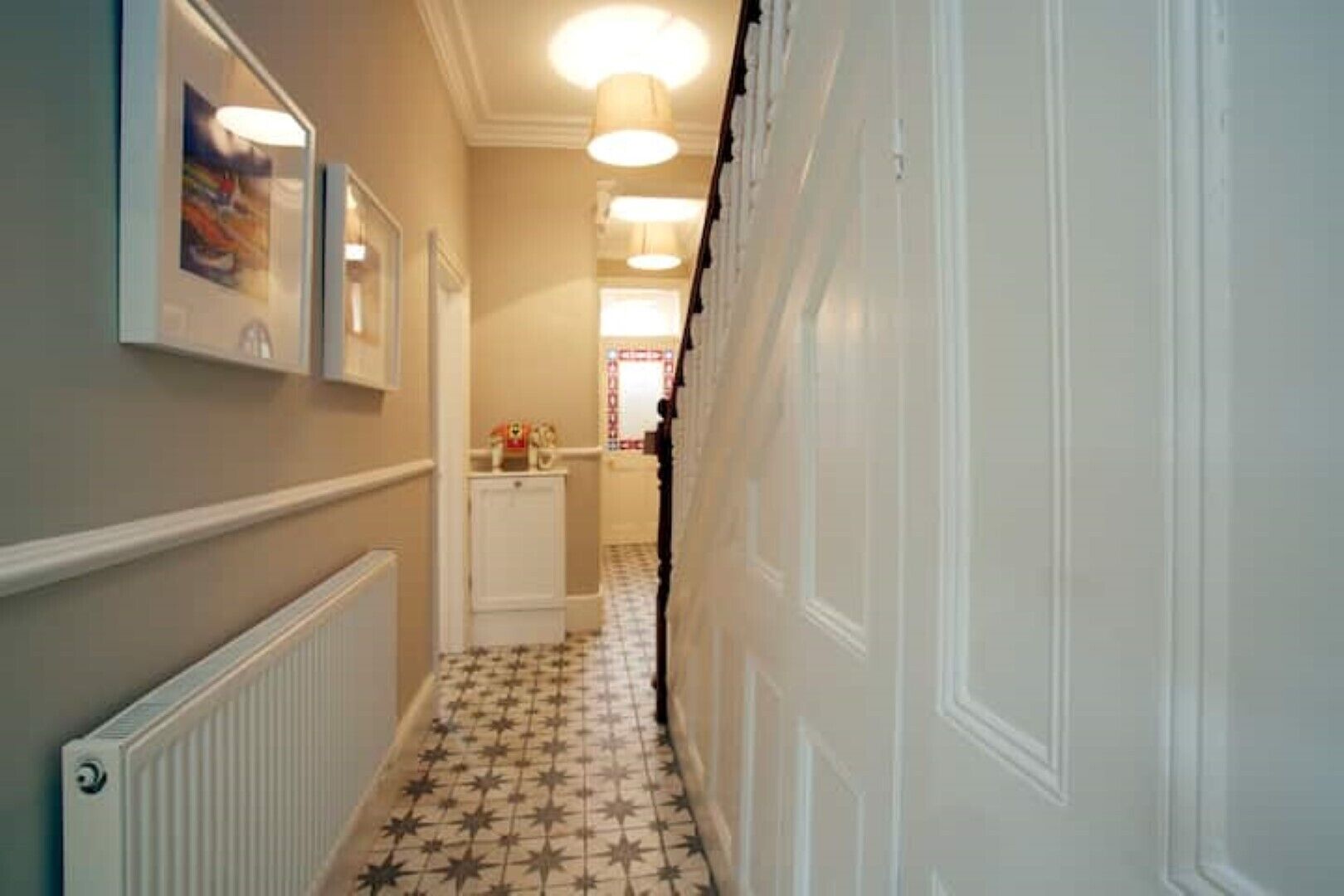 A narrow hallway with a radiator, a white cabinet, and a tiled floor.