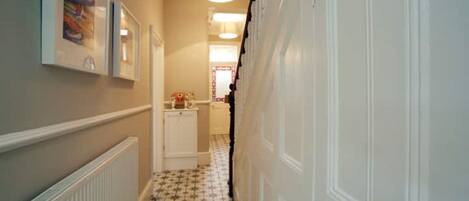 A narrow hallway with a radiator, a white cabinet, and a tiled floor.