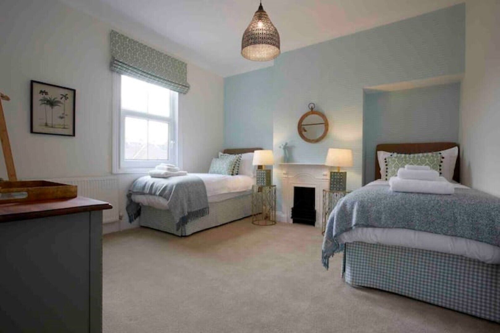 A bedroom with two beds, a fireplace, and a hanging light fixture.