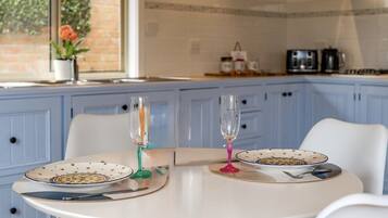 A kitchen with blue cabinets, a white table, two plates with a floral pattern, and two glasses.