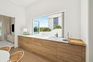 A modern bathroom with a large mirror, wooden cabinetry, a sink, and a window with a view of the outside.