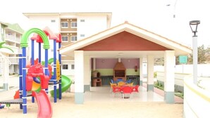 A covered outdoor area with a playground, a table with chairs, and a building in the background. - Remarkable 3-bed Apartment in Viana (Viana)