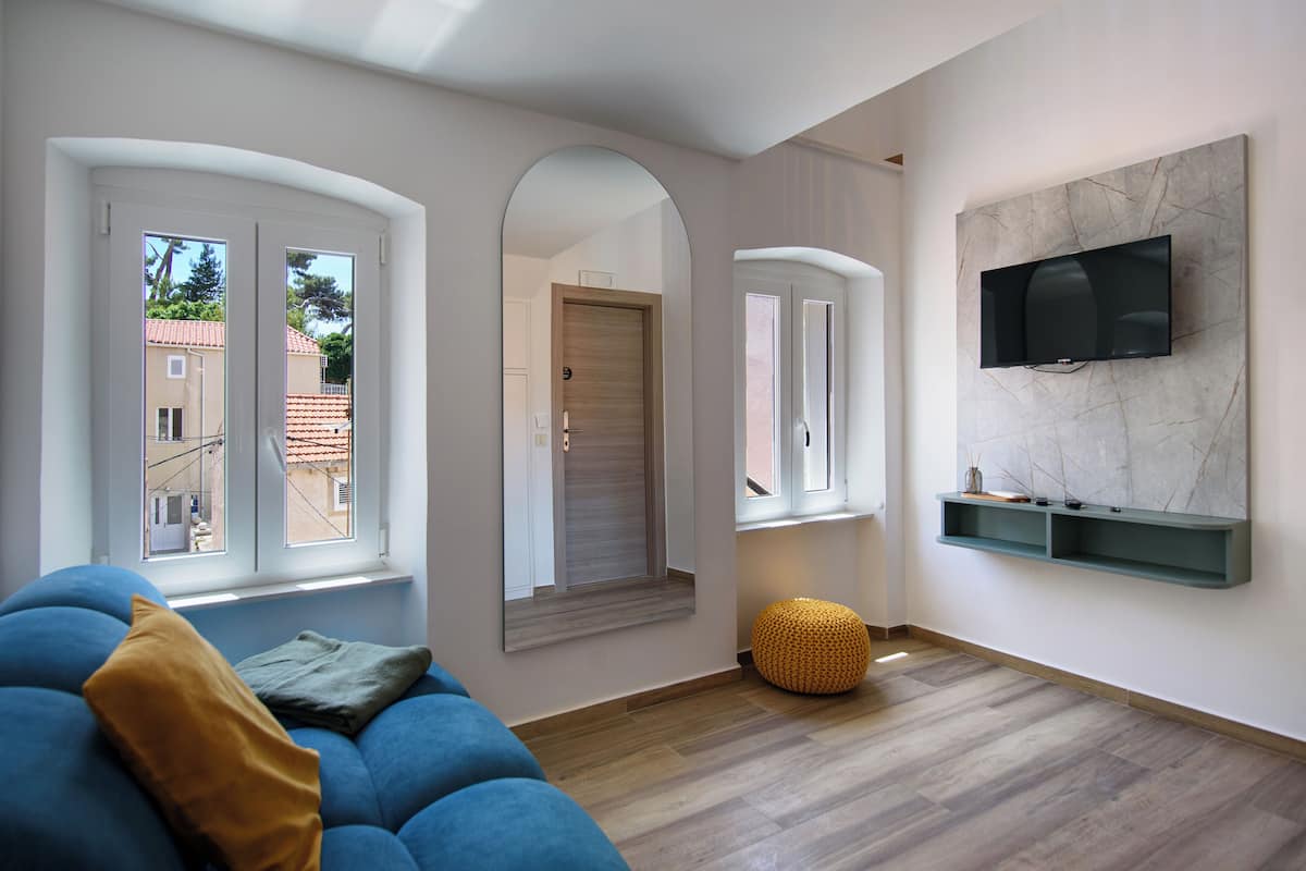 Una sala de estar moderna con un sofá azul, piso de madera y un televisor montado en la pared.