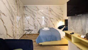 Una camera d'albergo moderna con un letto, una televisione e un pavimento in legno.