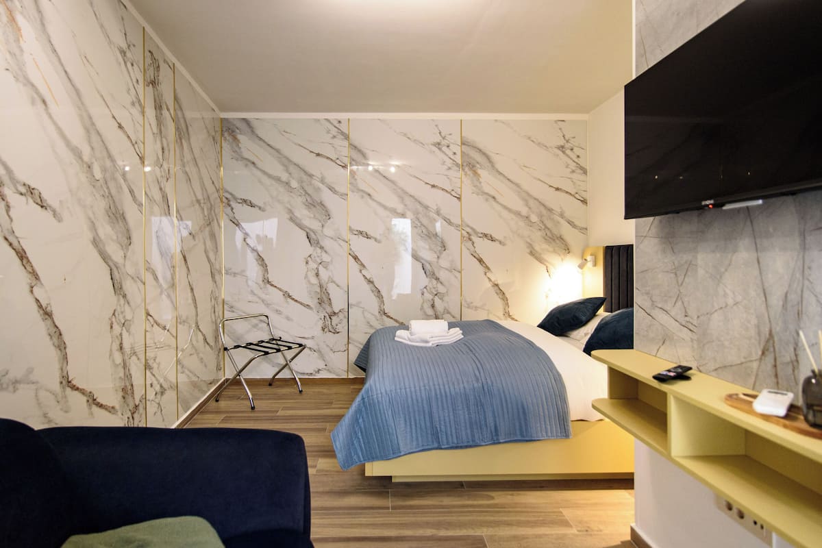 Una habitación de hotel moderna con cama, televisor y piso de madera.