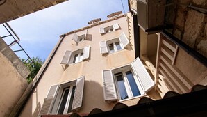 Un edificio con diverse finestre, alcune dotate di persiane, e un condizionatore d'aria ben visibile.