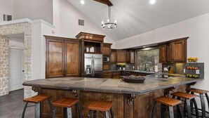 A spacious kitchen with a large island, wooden cabinets, and a stone backsplash. - The Sanctuary at Canyon Lake | 3 Bed, 3 Bath (Canyon Lake)