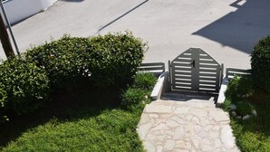 A stone pathway leading to a gated entrance surrounded by well-maintained hedges. - Lefteris Insta-worthy Studio With Garden View (Rhodes)