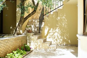 Guests can enjoy a serene outdoor space with a tree, planter, and steps leading up to an upper level.