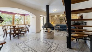A cozy living room with a stone fireplace, a dining area with wooden chairs, and a blue sofa. - Villa Ene in Pula  - Haus für 6 Personen (Pula)