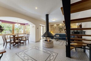 Cozy living area with a central fireplace, dining table, and comfortable seating.