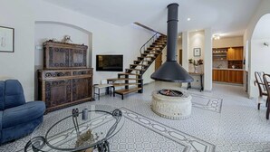 A spacious living area with a fireplace, a wooden staircase, and a modern kitchen in the background. - Villa Ene in Pula  - Haus für 6 Personen (Pula)