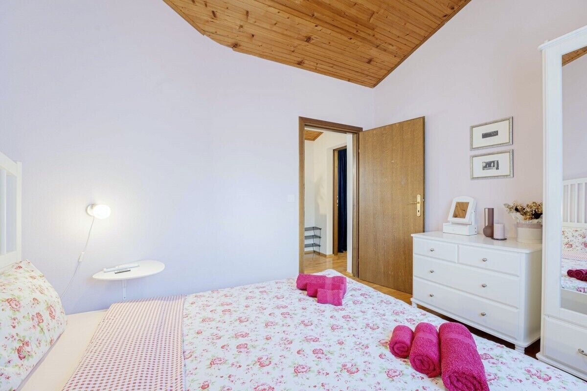 Una camera da letto con un letto, una cassettiera, un comodino e un soffitto con travi in legno.