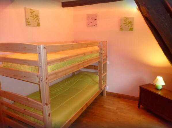 Habitación con literas, cabecero de madera, mesita de noche con lámpara y decoración en la pared.