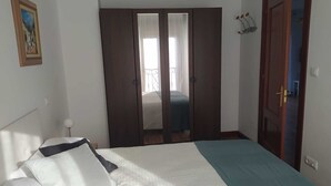 A bedroom with a bed, a wardrobe, and a door leading to another room.