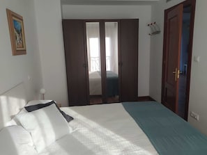Una camera da letto con un letto, un armadio e una porta che dà su un'altra stanza.
