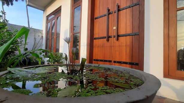 Une cour intérieure agrémentée d’un élément décoratif aquatique, de portes en bois et de plantes en pot.