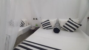 Une chambre d’hôtel avec un lit, des oreillers, une table de chevet et une petite table.
