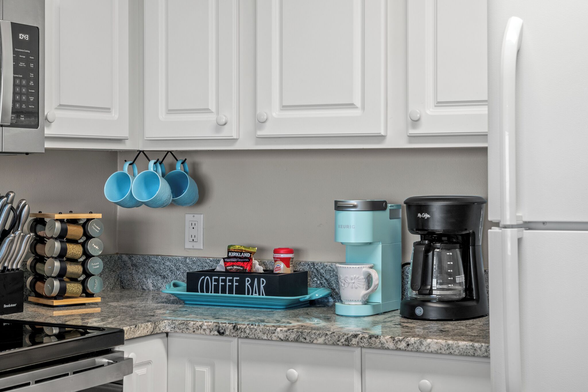 A kitchen with white cabinets, a coffee maker, a coffee pot, and a coffee bar sign.