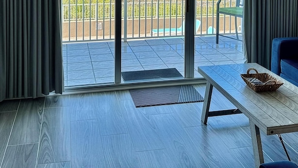 Una habitación con vista al mar, una puerta corrediza de vidrio, una mesa y una silla.