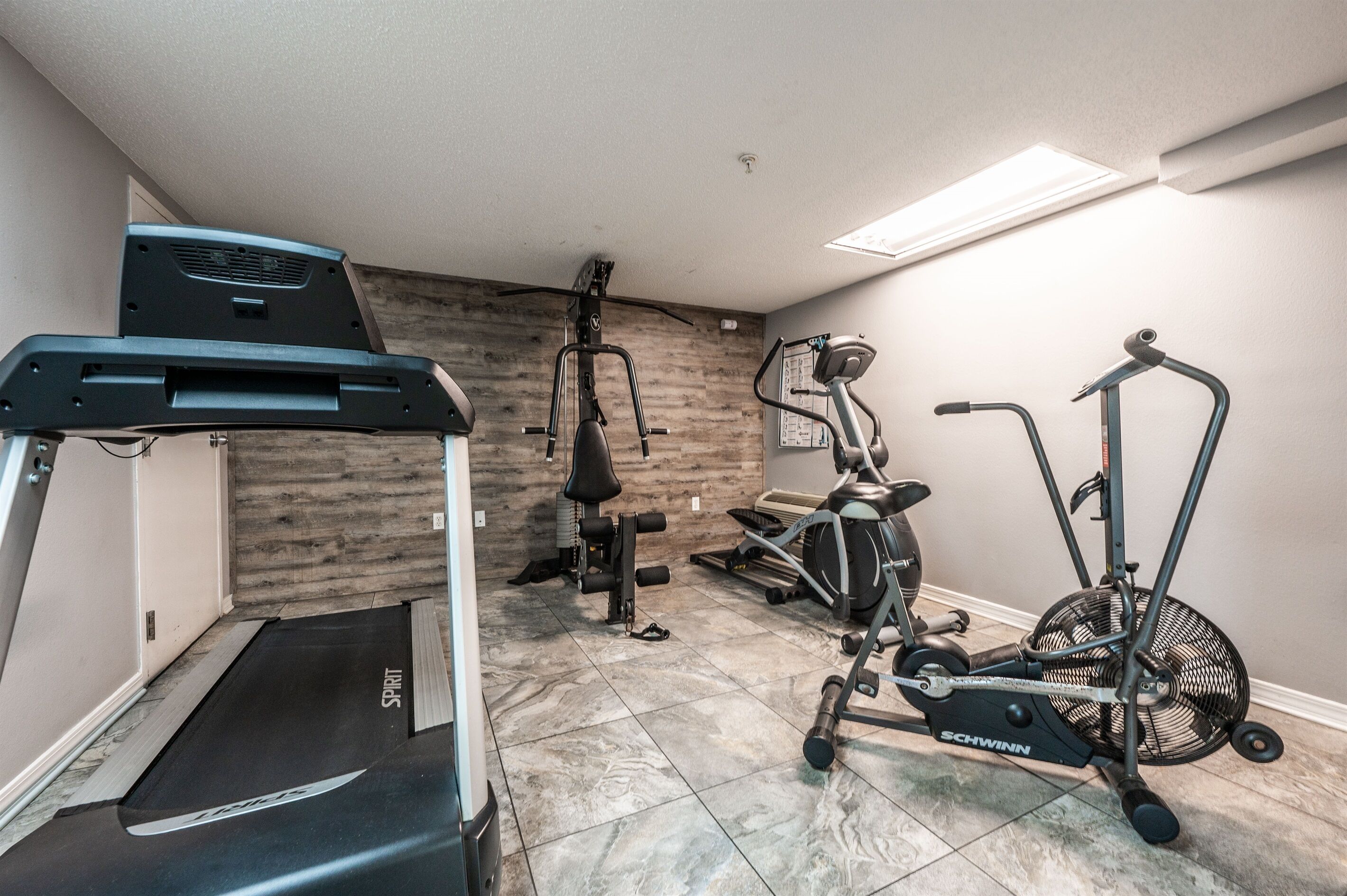 A home gym with a treadmill, elliptical, and stationary bike.