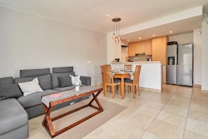 A modern living room with a sofa, coffee table, and dining area with chairs.