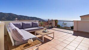 Un balcon avec un canapé, une petite table et une vue sur la mer.