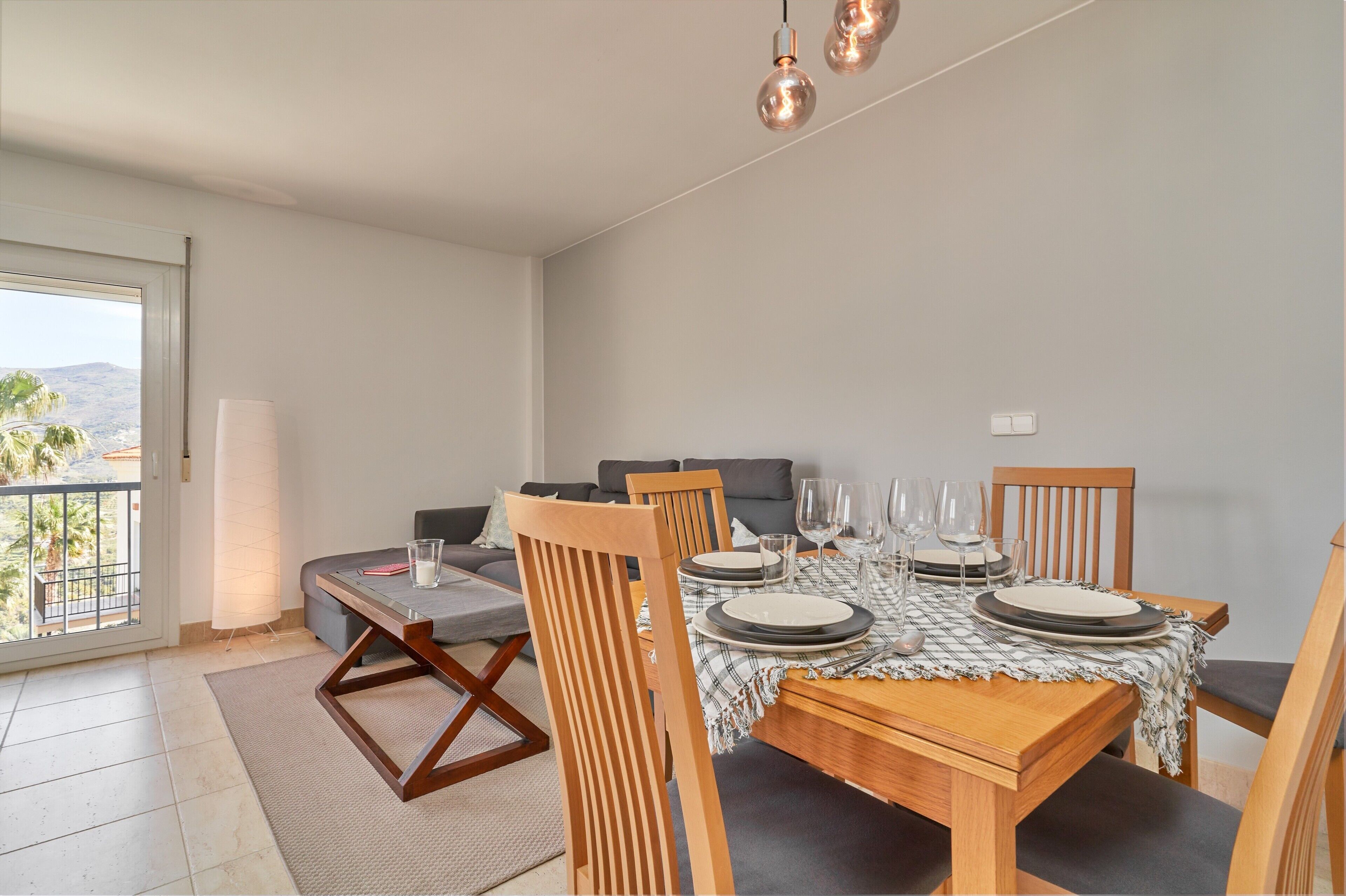 Een eetgedeelte met een tafel voor vier personen, een bank en een balkon met uitzicht.