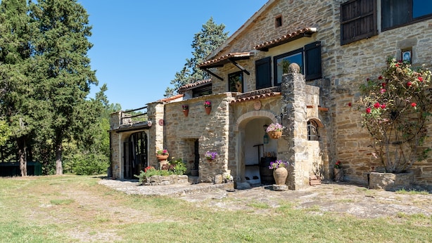 Un edificio de piedra con patio, arcos y plantas en macetas.