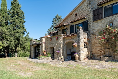 A stone building with a courtyard, arched doorways, and potted plants.