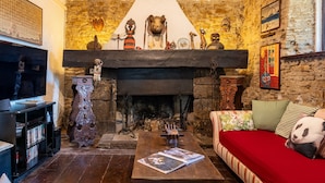 Una sala de estar acogedora con chimenea, televisión y un sofá con una manta roja.