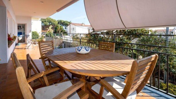 A wooden table with chairs on a balcony with a view of houses and greenery. - Millenium by Interhome (Premià de Dalt)