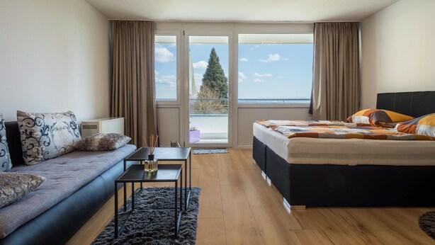 Een slaapkamer met een bed, een bank, een bijzettafeltje en uitzicht op de omgeving.
