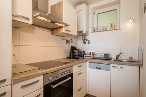 A compact kitchen with a built-in oven, a dishwasher, and a coffee maker.