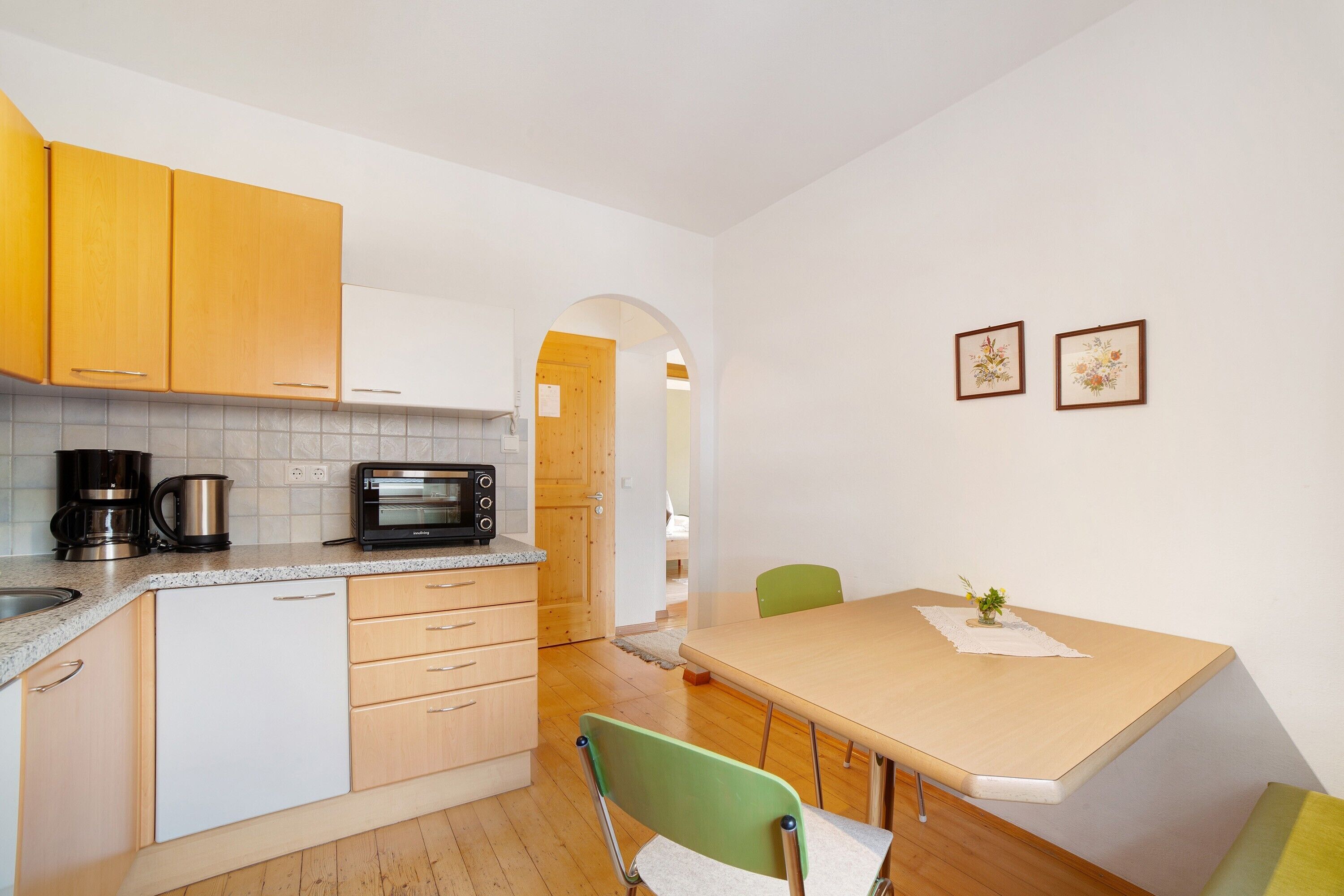 Una cocina pequeña con microondas, cafetera y armarios de madera.