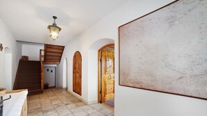 A hallway with a wooden staircase, a map on the wall, and a wooden door.